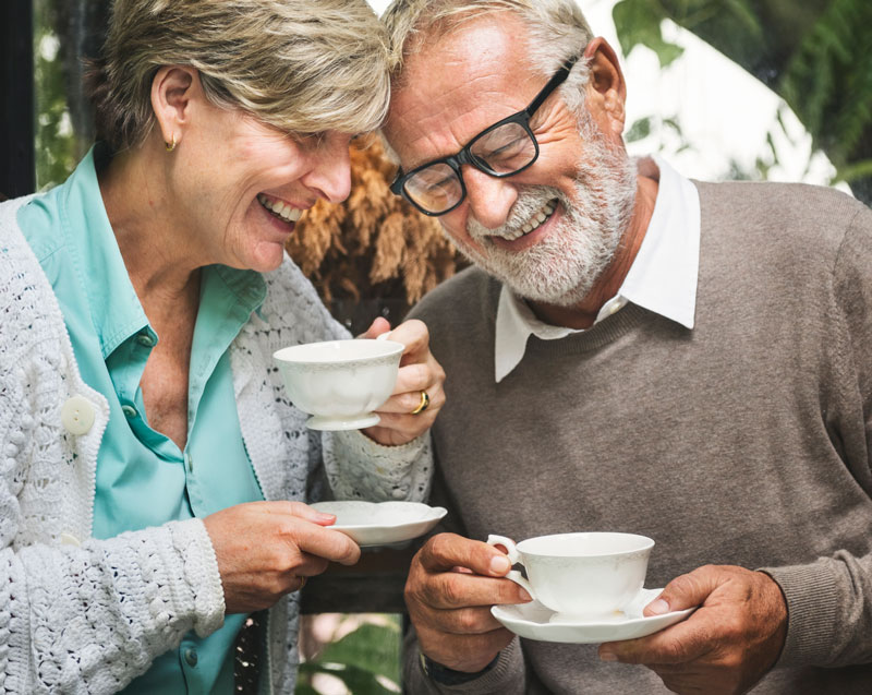 An older man and woman drinking tea and laughing