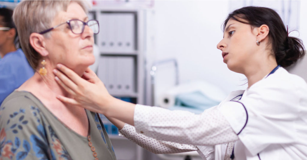 A female healthcare worker inspects a female patient's neck.