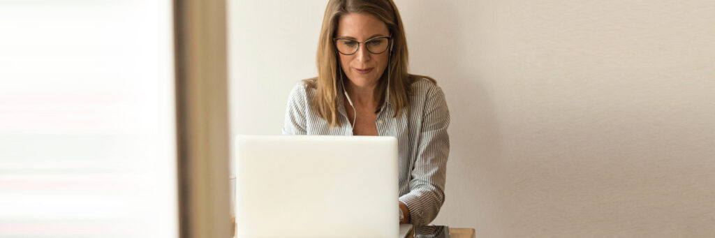 A woman using a laptop to access her health plan's PBM pharmacy savings tool.